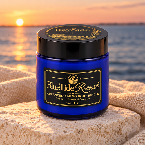 BlueTide Renewal body butter in its cobalt-blue jar beside linen and sea glass at sunset.