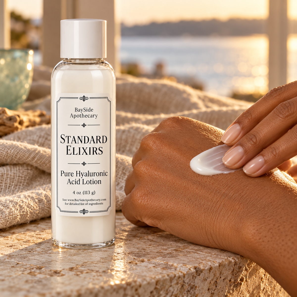 White Standard Elixirs lotion being spread onto the back of a hand beside its bottle.