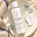Standard Elixirs lotion bottle beside a smooth white lotion swatch on ivory ceramic.